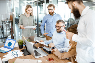 Wall Mural - group of diverse colleagues working in the office, having discussion or small conference on a workin
