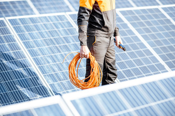 Wall Mural - well-equipped worker in protective orange clothing servicing solar panels on a photovoltaic rooftop 