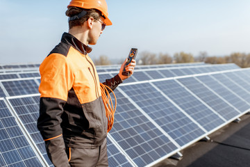 Wall Mural - well-equipped worker in protective orange clothing servicing solar panels on a photovoltaic rooftop 