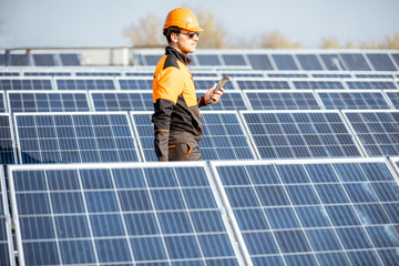 Wall Mural - well-equipped worker in protective orange clothing servicing solar panels on a photovoltaic rooftop 