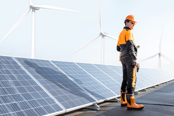 Wall Mural - well-equipped worker in protective orange clothing examining solar panels on a photovoltaic rooftop 