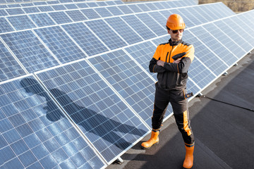 Wall Mural - portrait of a well-equipped worker in protective orange clothing examining solar panels on a photovo