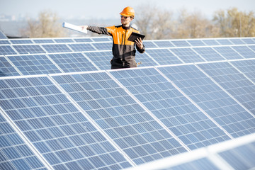 Wall Mural - view on the rooftop solar power plant with engineer in protective workwear walking and examining pho