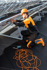 Wall Mural - Well-equipped electrician connecting wires of solar panels on a rooftop photovoltaic power plant. Concept of installing solar stations