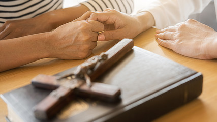 Wall Mural - Christian woman praying with hands together on holy bible and wooden cross. Woman pray for god blessing to wishing have a better life and believe in goodness.