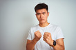 © Krakenimages.com - Young asian chinese man wearing t-shirt standing over isolated white background Ready to fight with fist defense gesture, angry and upset face, afraid of problem