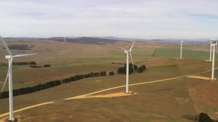 Wall Mural - aerial view of an array of large wind turbines rotating to create kinetic energy for renewable energ