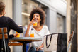 © mimagephotos - two female friends drinking and laughing at outdoor cafe
