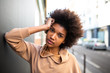 Side of beautiful young black woman with afro hair leaning against wall by street