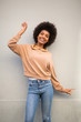 © mimagephotos - beautiful young african american woman smiling with arm raised against gray wall
