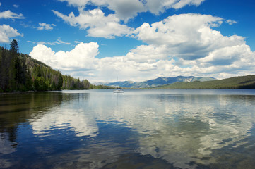 Wall Mural - Panoramic view of puffy white clouds reflecting on the surface of a tranquil Alturas Lake in the Rocky Mountains of Idaho, USA