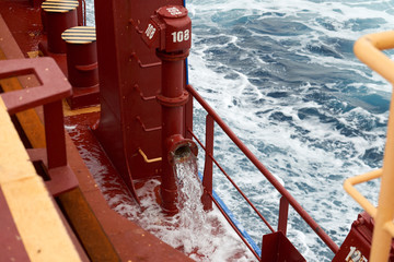 View of Ballast Water exchange process onboard of a ship using flow-through method underway in open ocean. Overflow method through ballast tank air head.