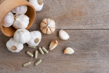 Garlic Bulb With Cloves And Garlic Capsules Isolated On Wood Table  Background. Natural Herbal Medicine Plant And Vitamin Supplement Concept. Top View. Flat Lay. 