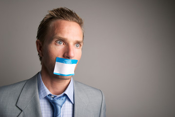 Dazed businessman silenced with a name tag sticker over his lips