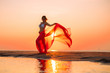 Woman posing with piece of clothing on the beach at sunset