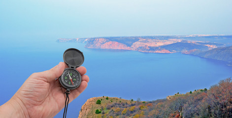 hand with compass on background of sea