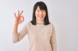 © Krakenimages.com - Young beautiful chinese woman wearing turtleneck sweater over isolated white background smiling positive doing ok sign with hand and fingers. Successful expression.
