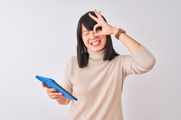 Wall Mural - Beautiful chinese woman using blue tablet standing over isolated white background with happy face smiling doing ok sign with hand on eye looking through fingers