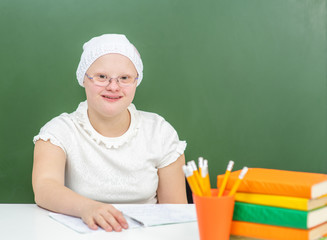 Young girl with Down Syndrome with books at school. Empty space for text