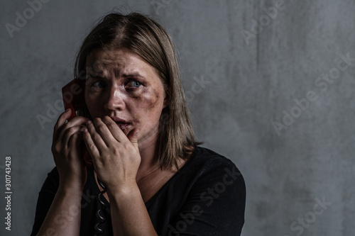 Scared  woman victim of domestic violence and abuse asks for help by phone. Looking away. Empty space for text