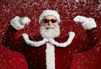 Wall Mural - Waist up portrait of funky Santa wearing sunglasses and smiling at camera ready to enjoy Christmas party in snow