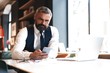 © opolja - Business man in formal clothing using mobile phone. Serious businessman using smartphone at work