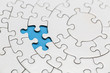 © Tinnakorn - Unfinished white jigsaw puzzle pieces on blue background, The last missing piece of the jigsaw puzzle.