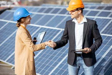 Wall Mural - business man and woman dressed in the suits having a deal, shaking hands while standing on a solar p