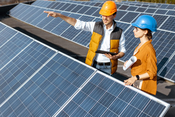 Wall Mural - two engineers or architects examining the construction of a solar power plant, standing with digital