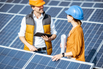 Wall Mural - two engineers or architects examining the construction of a solar power plant, standing with digital