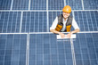 © rh2010 - Portrait of a handsome engineer in protective helmet standing with blueprints on a solar power plant. Solar station development concept