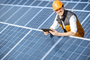 Wall Mural - portrait of a happy engineer in protective helmet standing with digital tablet on a solar power plan