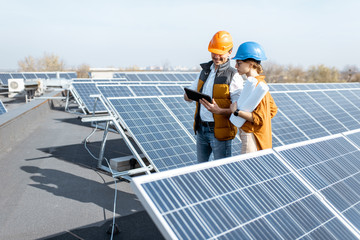 Wall Mural - two engineers or architects examining the construction of a solar power plant, walking with digital 