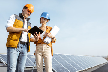 Wall Mural - two engineers or architects examining solar power plant with a digital tablet. solar station develop