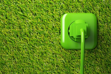 Green power cord in wall socket on grass background with copy space - eco or green power consumption concept