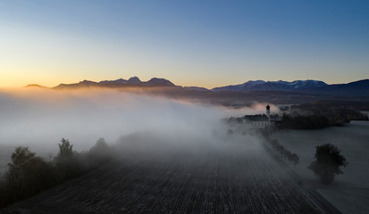 Wall Mural - beautiful foggy autumn morning in bavaria - aerial view of wilparting church before alps in chiemgau