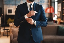Handsome Businessman Adjusting His Sleeves While Standing In Modern Office