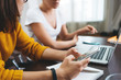 © leonidkos - Close-up of female hands hold modern smartphone at her workplace at office. Group of posotive woman working together and using digital gadgets at open space