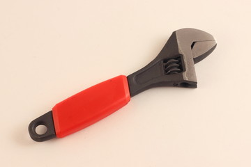 Single close adjustable wrench tool with red plastic handle on white background closeup