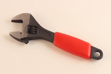 Close up ready to use monkey wrench instrument with red handle on white background