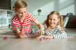 © spass - Portrait of two cheerful children laying on the floor and playing with colorful dices