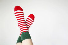 Female Feet In Christmas Socks On White Background. Concept Of New Year Celebration, Elf Costume