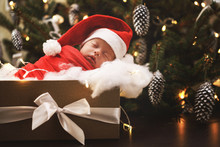 Cute Newborn Baby Wearing Santa Claus Hat Is Sleeping In The Christmas Gift Box
