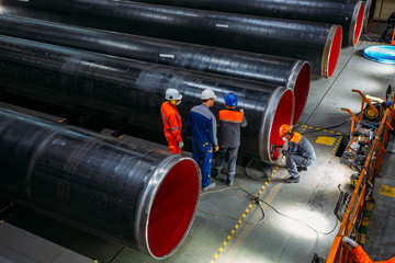 Wall Mural - Engineers examine new coated pipe in factory