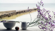 Beautiful Composition Of Heather And Chestnut Among A Wonderful Breakfast On The Beach, Against The Background Of The Ocean And The Blue Sea.