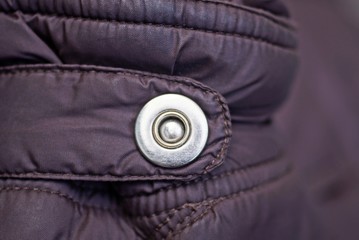 gray metal button rivet on the brown fabric of the sleeve