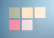 5 blank empty white and pastel colors sticky notes on clean blue background with free space, from top view with copy space