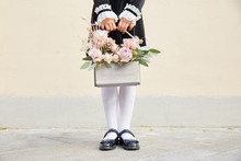 A Schoolgirl Handing A Basket Of Flowers On The Street At The Wall