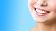 Stomatology concept. Partial portrait of a girl with white teeth smiling. Closeup of young woman at dentist's, studio, indoors. isolated on blue background.