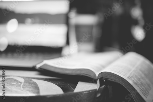 Fotografía Grayscale closeup shot of an open bible on the table wit ha blurred background